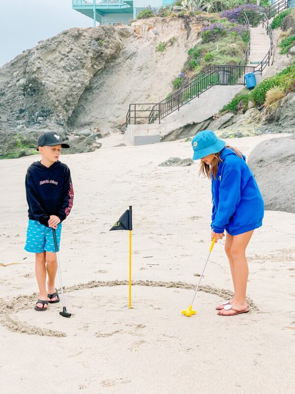 Two Kids Playing Golf on the Beach Sand